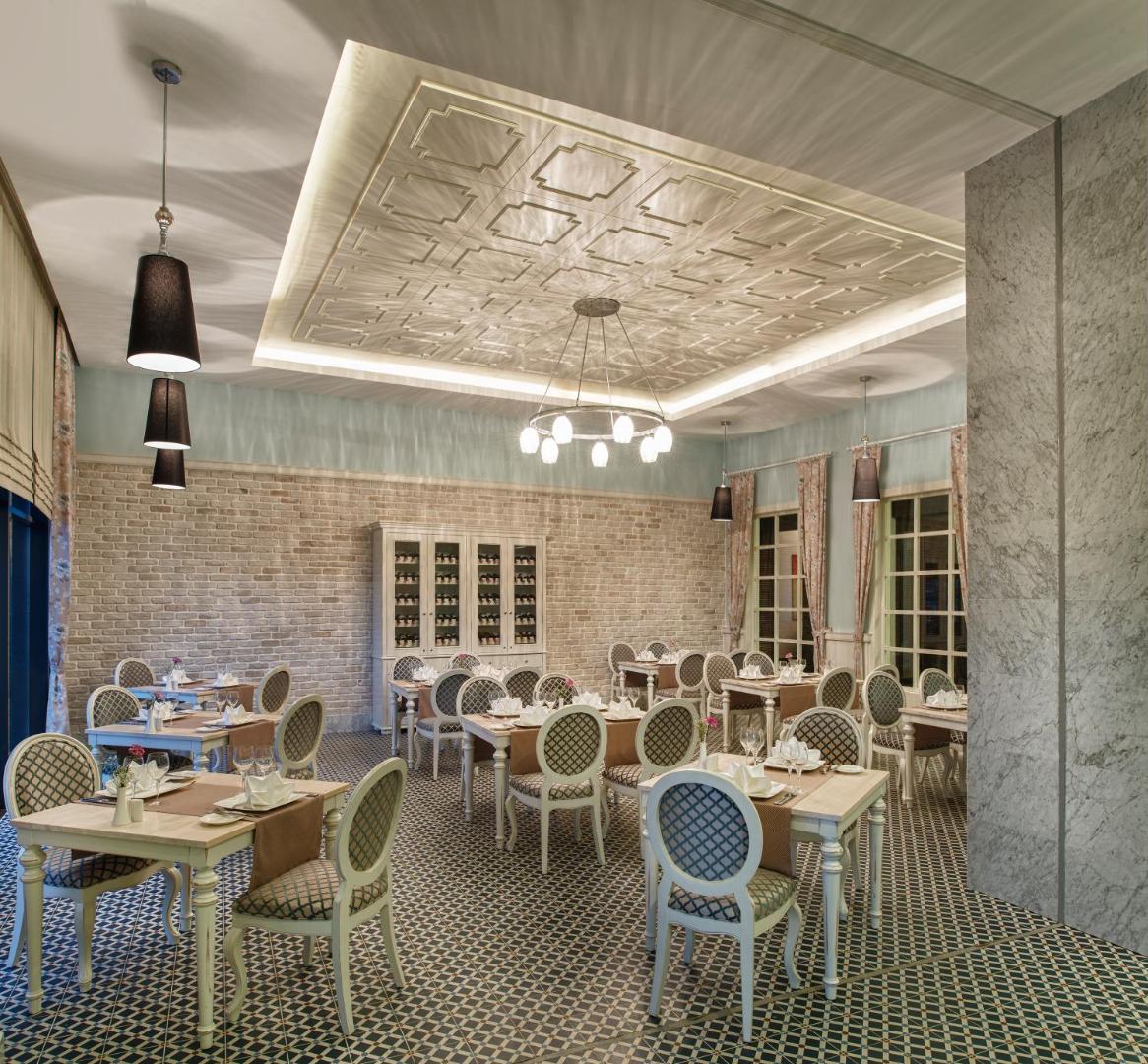Aska Lara Resort & Spa klasiska stila restorāna interjers ar gaišām mēbelēm un dekoratīviem griestiem