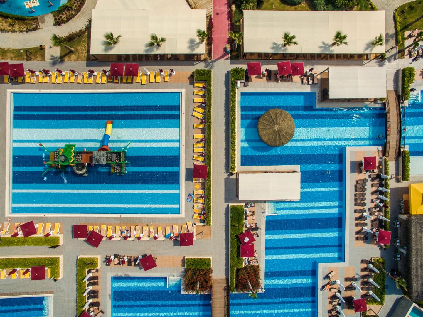 Aska Lara Resort & Spa skats no putna lidojuma uz plašo baseinu kompleksu un bērnu ūdens atrakciju parku Antālijā
