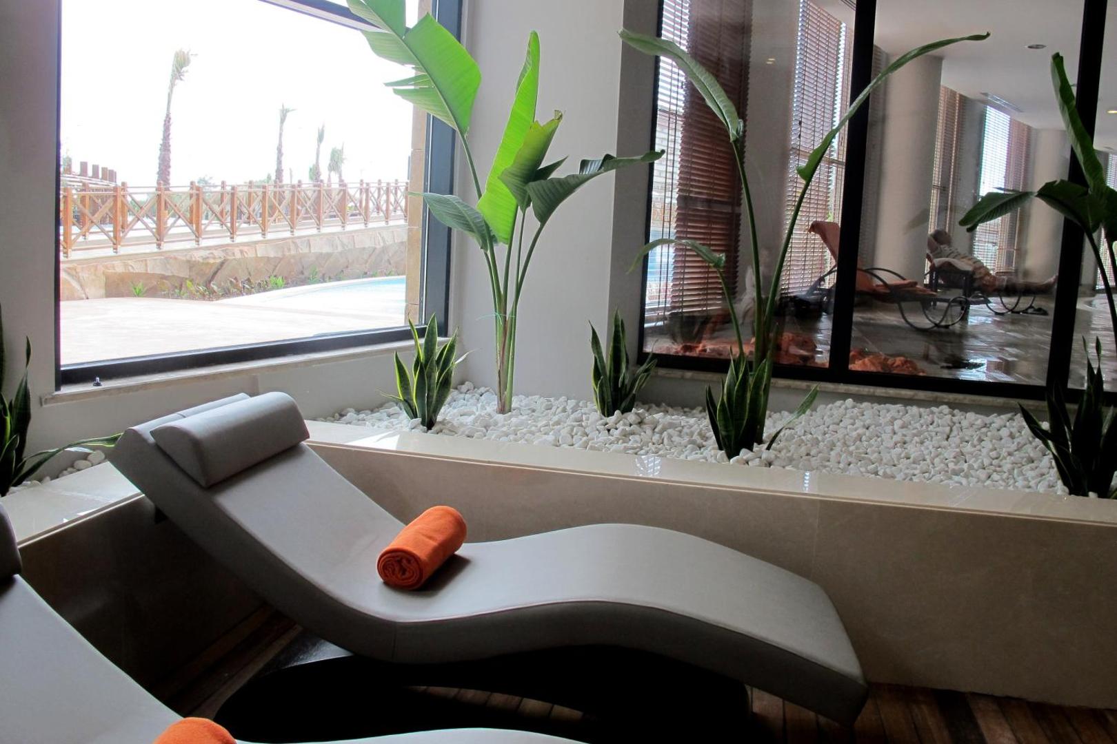 Aska Lara Resort & Spa spa atpūtas telpa ar ergonomiskiem zviļņiem, dekoratīviem augiem un skatu caur lielajiem logiem