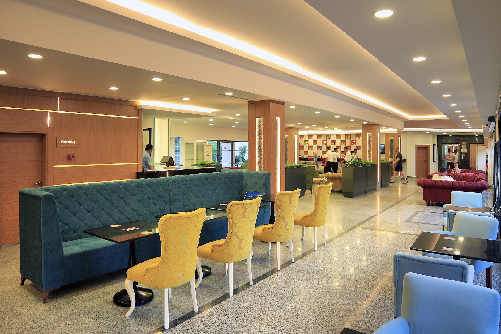 Viesnīcas Club Aqua Plaza vestibils un lobby bārs ar moderniem dzelteniem krēsliem un tirkīza dīvānu — gaišs interjers viesu uzņemšanai