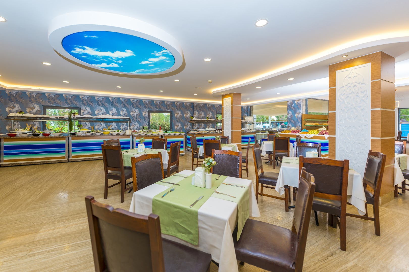 Viesnīcas Club Aqua Plaza restorāna interjers ar dekoratīviem griestu elementiem un bufetes līniju fonā