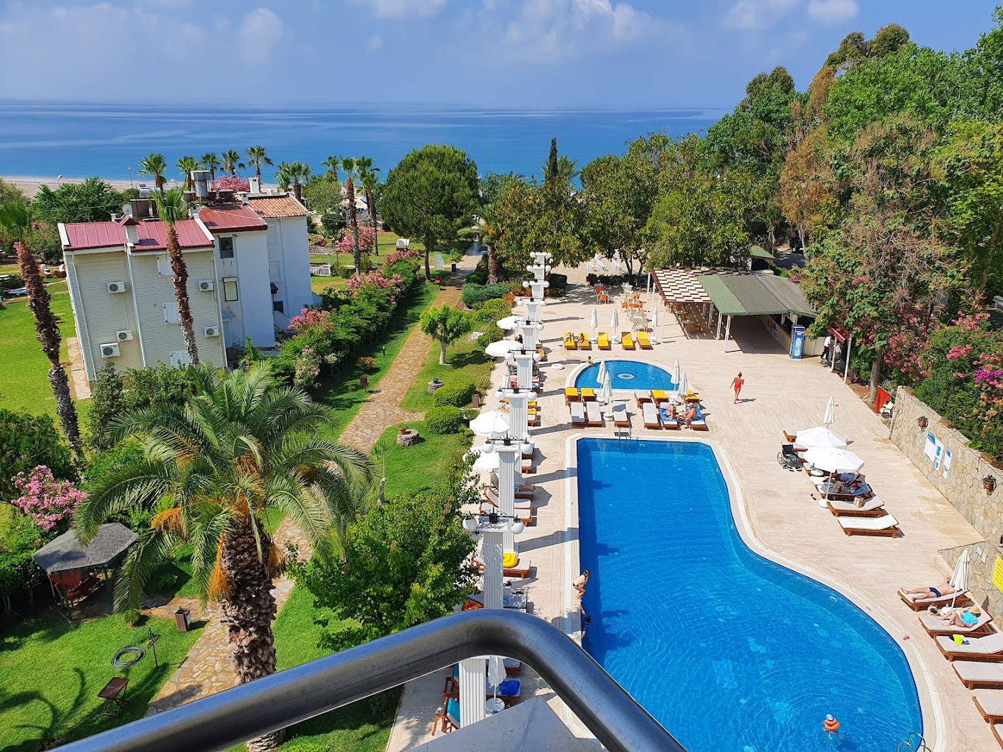 Club Aqua Plaza āra baseins ar ziliem ūdeņiem, sauļošanās krēsliem un palmām Alānijas piekrastē, skats no augšas