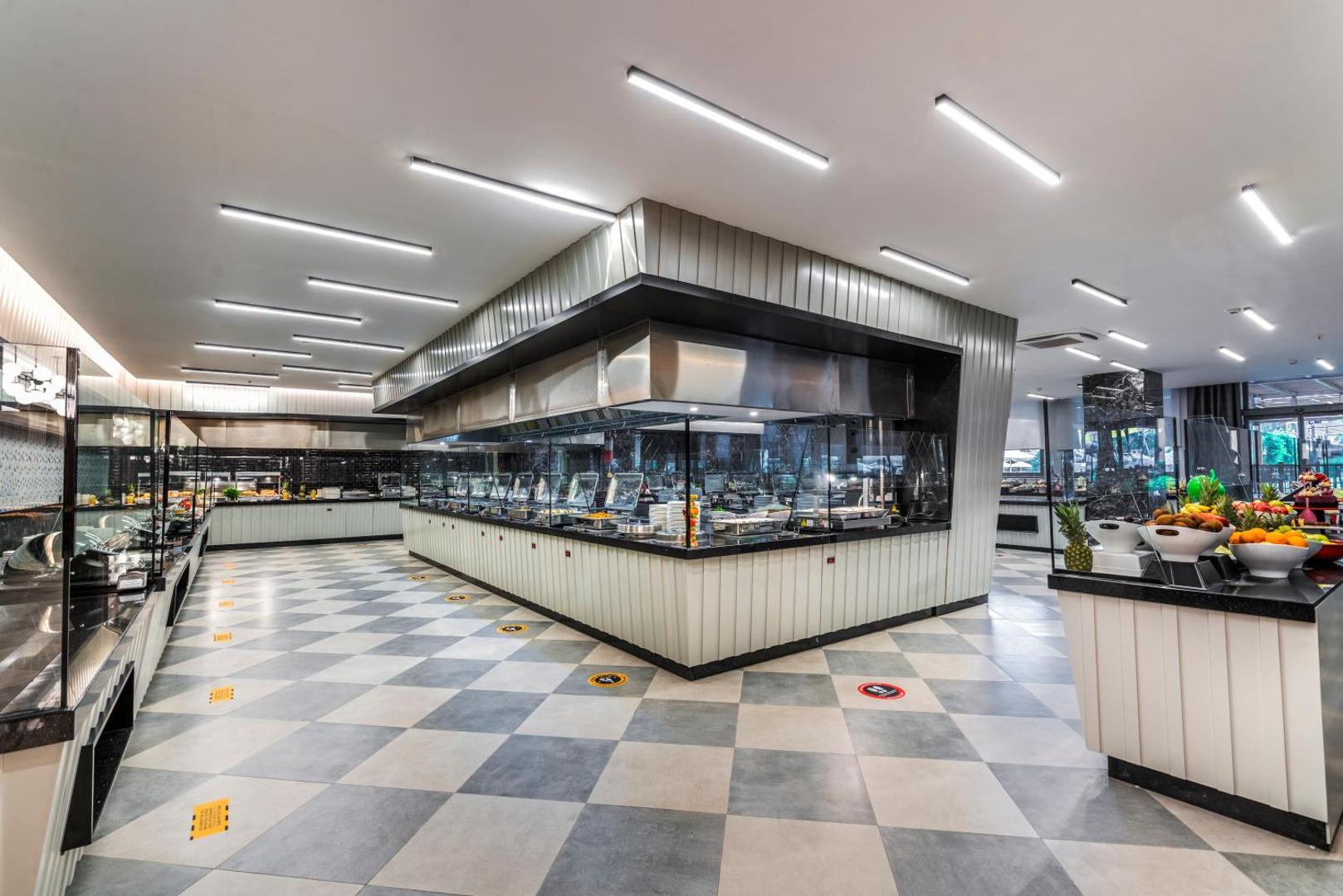 Arnor De Luxe Hotel & Spa galvenā restorāna bufetes zona ar plašu ēdienu izvēli, modernu apgaismojumu un rūtainu grīdas flīžu dizainu.