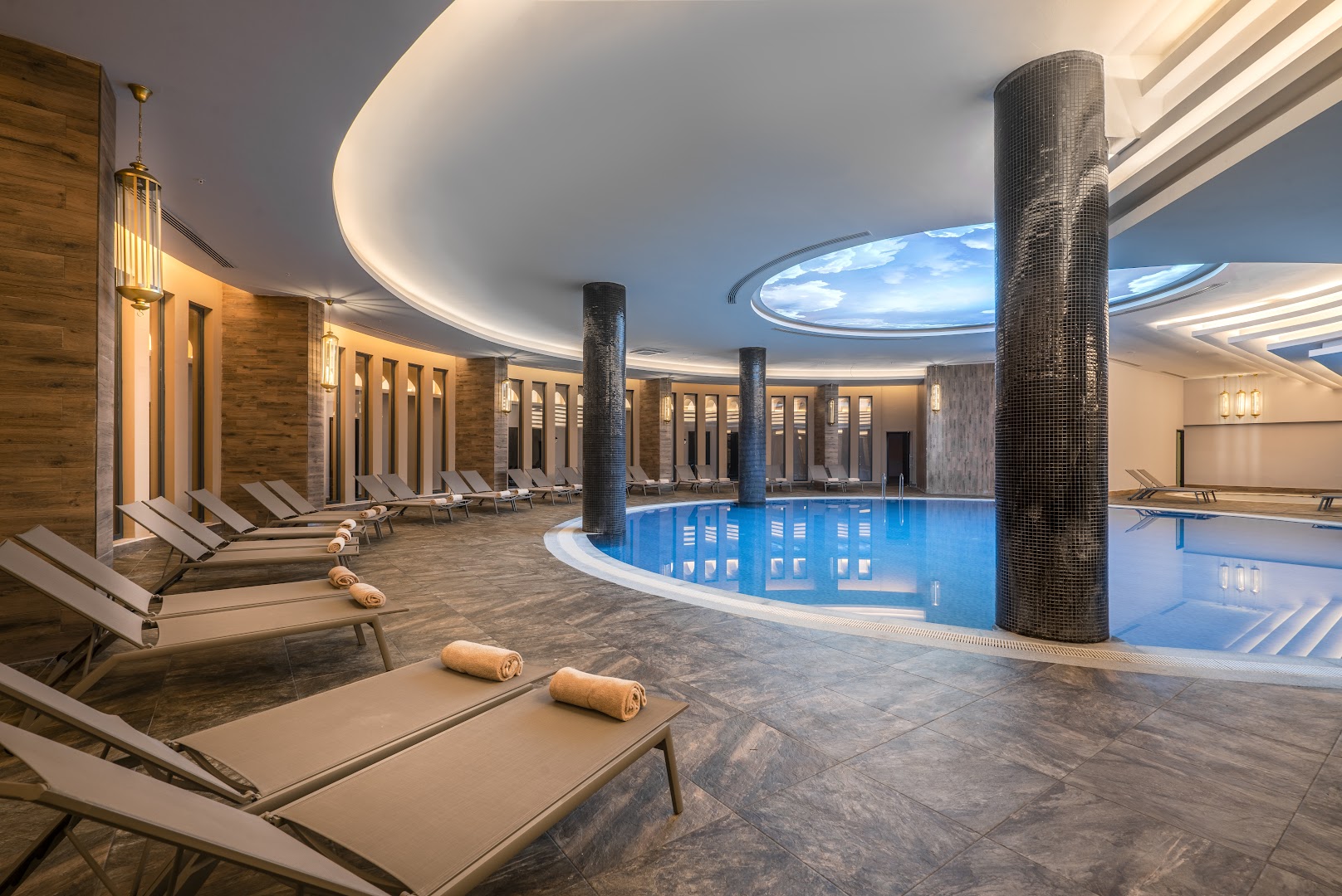 Arnor De Luxe Hotel & Spa iekštelpu baseins Sidē ar modernu apgaismojumu, atpūtas krēsliem un dekoratīvām kolonnām spa zonā