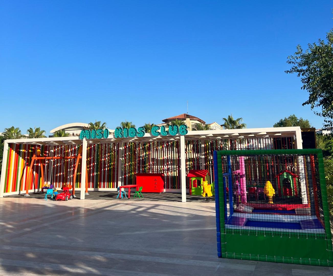 Megasaray Westbeach Antalya bērnu klubs Misi Kids Club āra teritorijā ar šūpolēm, slidkalniņiem un batutu zem skaidrām debesīm