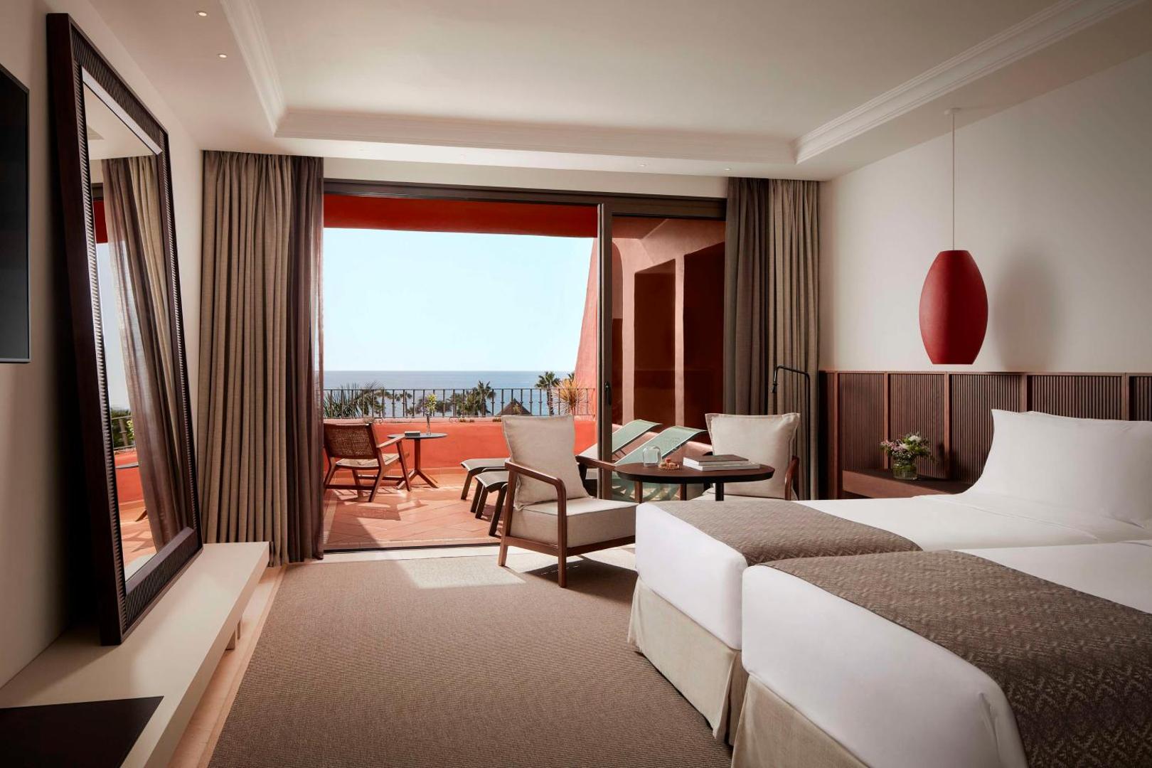 Tivoli La Caleta Tenerife Resort divvietīgs numurs ar atsevišķām gultām, lielu spoguli un izeju uz terasi ar skatu uz okeānu