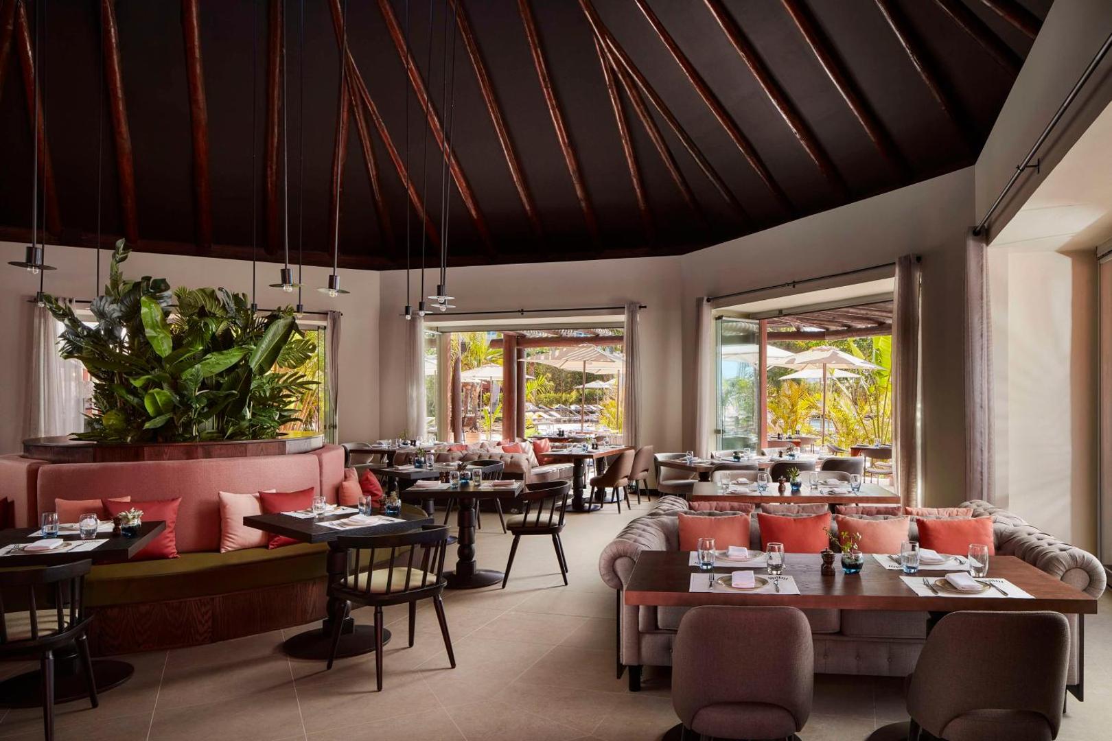 Tivoli La Caleta Tenerife Resort restorāns ar modernu interjeru, apaļu dīvānu un skatu uz āra terasi Tenerifes piekrastē
