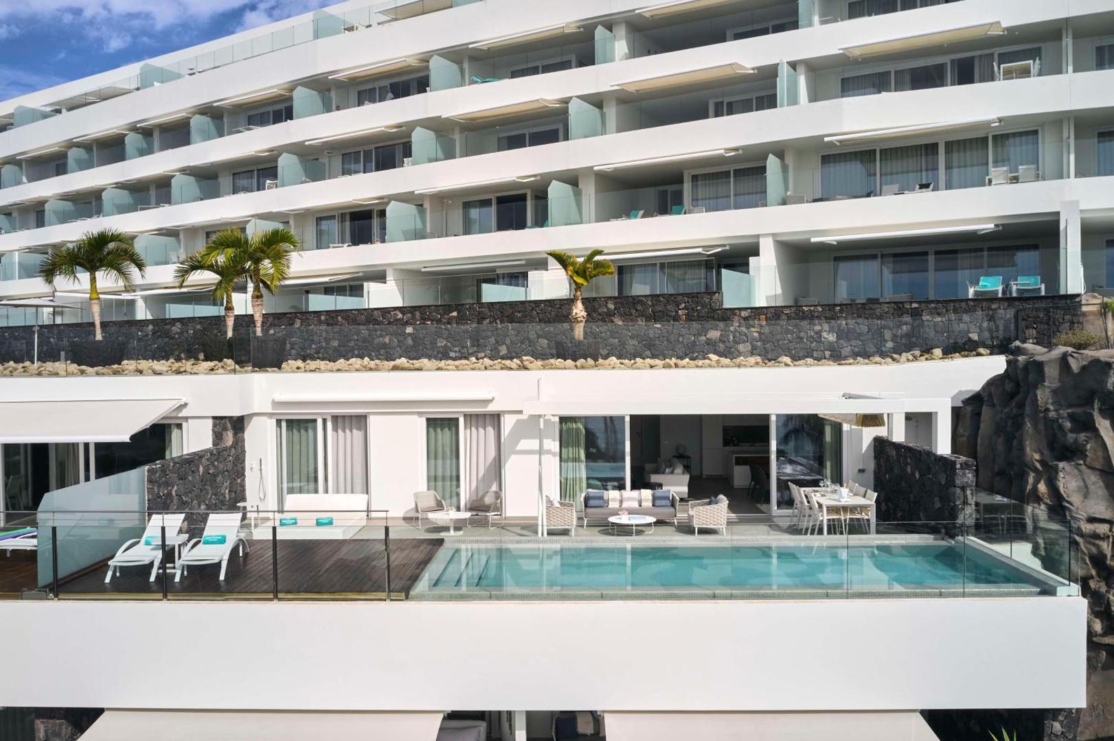 Royal Hideaway Corales Suites fasāde Tenerifē ar luksusa numuriem, kuriem ir privātas terases un baseini ar skatu uz okeānu.