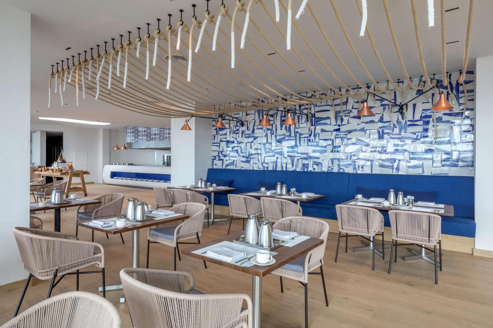Royal Hideaway Corales Beach restorāna interjers Tenerifē ar modernām mēbelēm, ziliem akcentiem un virvju dekorācijām pie griestiem.