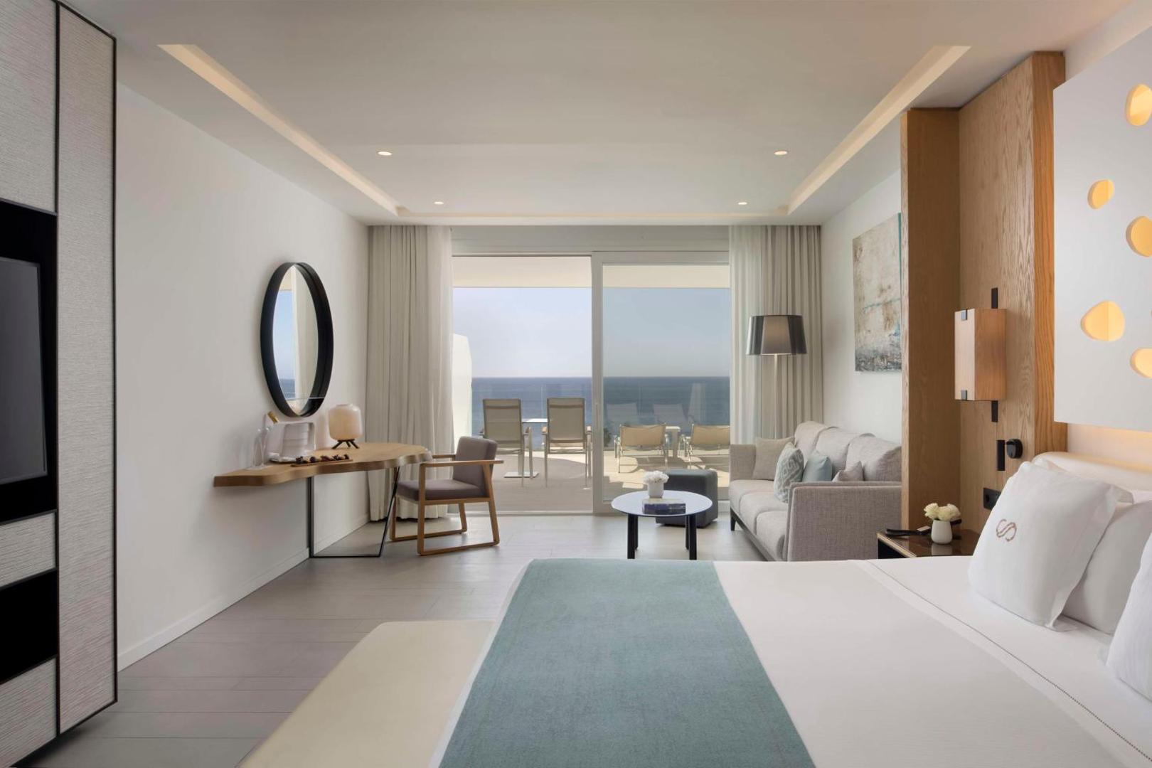 Royal Hideaway Corales Beach moderns numurs ar skatu uz okeānu Tenerifē — gaišs interjers, atpūtas zona ar dīvānu un plaša terase