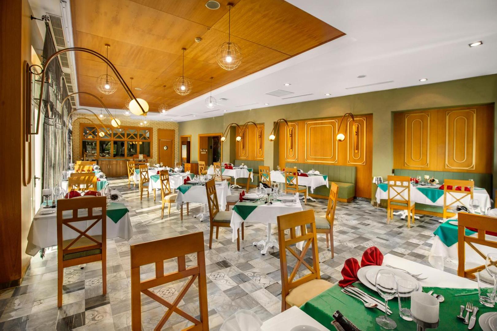 Sherwood Blue Belek a la carte restorāna interjers ar balti klātiem galdiem, koka apdari un siltu apgaismojumu