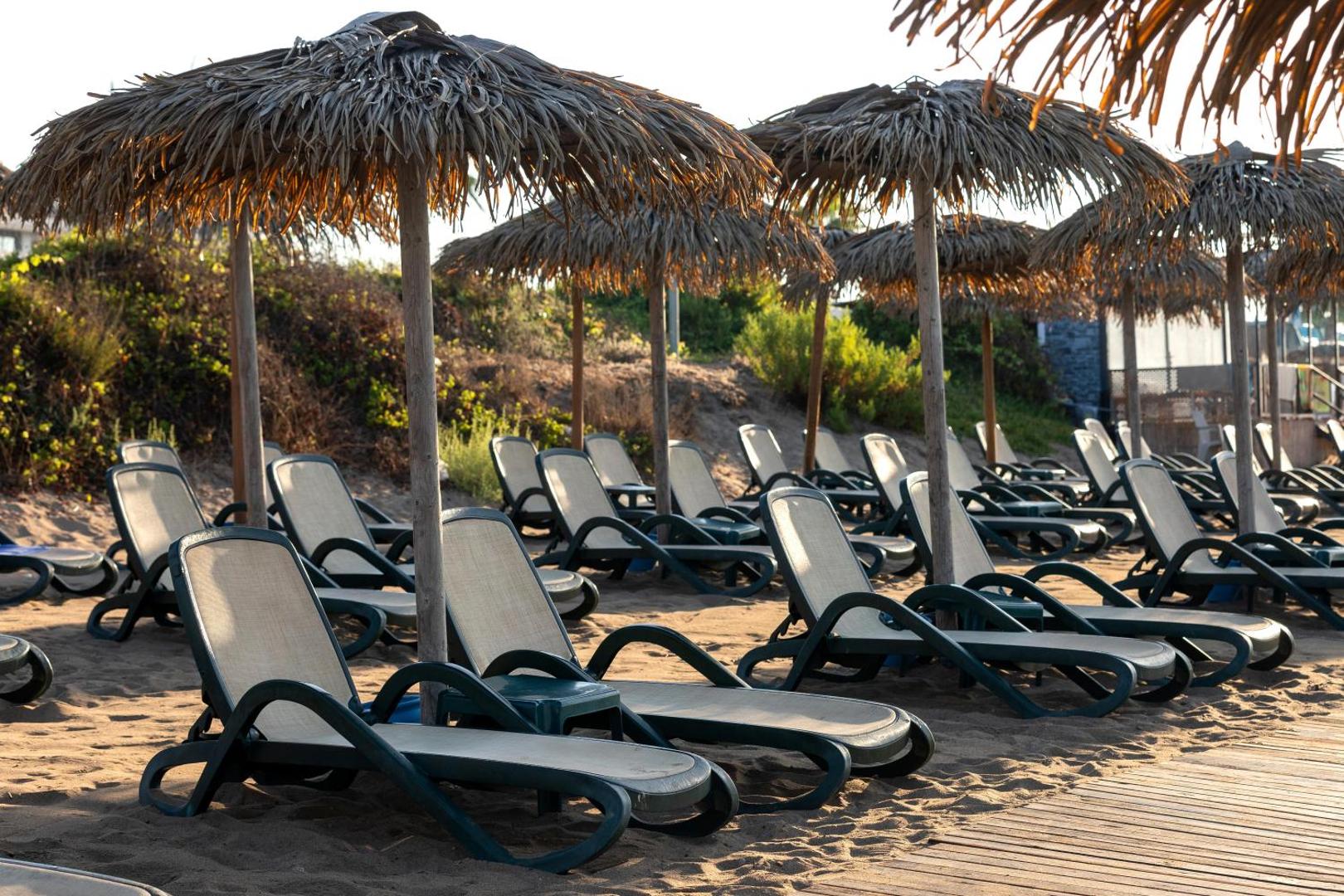 Sherwood Blue Belek pludmales zona ar salmu saulessargiem un ērtiem sauļošanās krēsliem smilšainajā Belekas piekrastē