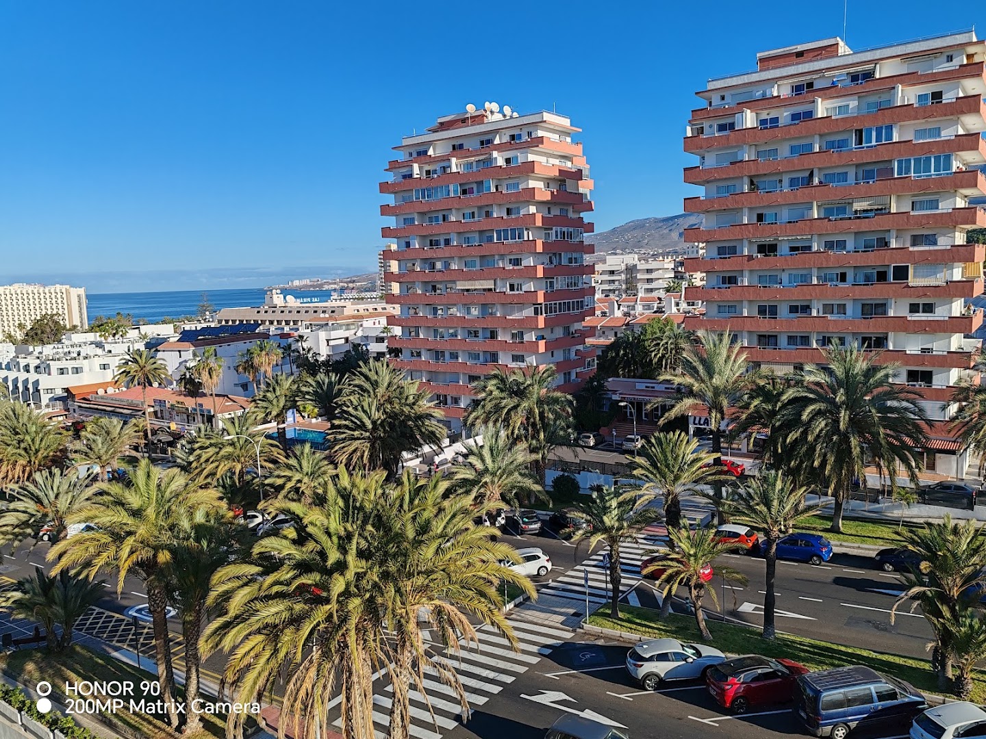 Kn Columbus Aparthotel skats no augšas uz kūrorta ēkām, palmām un okeāna piekrasti Plaja de las Amerikasā, Tenerifē