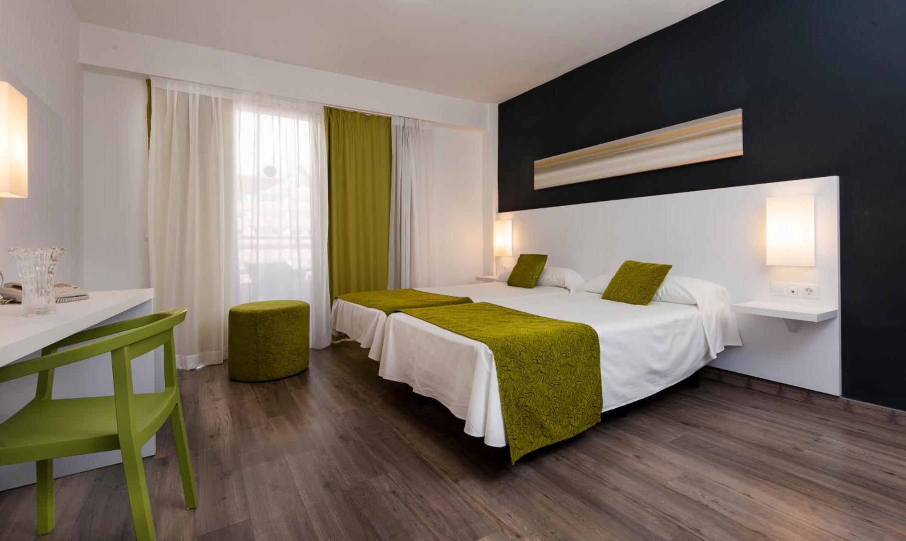 Kn Columbus Aparthotel numura interjers ar zaļiem tekstila akcentiem un darba zonu — plašs un saulains numurs