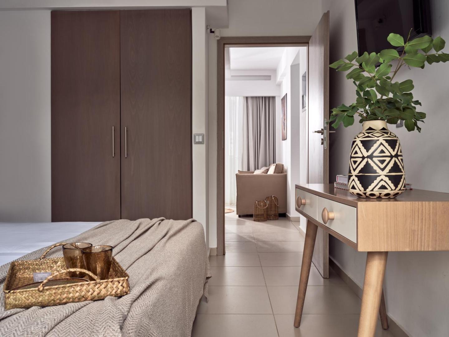 Troulis Apart-Hotel apartamentu interjers ar skapi, darba virsmu un skatu uz viesistabas zonu gaišos toņos