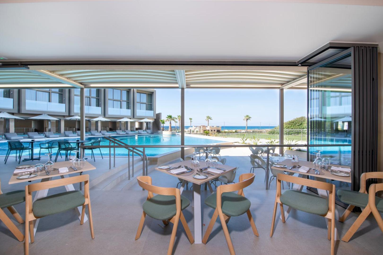 Skats no Ventale Island Breeze Resort restorāna terases uz baseinu un jūras horizontu Krētā