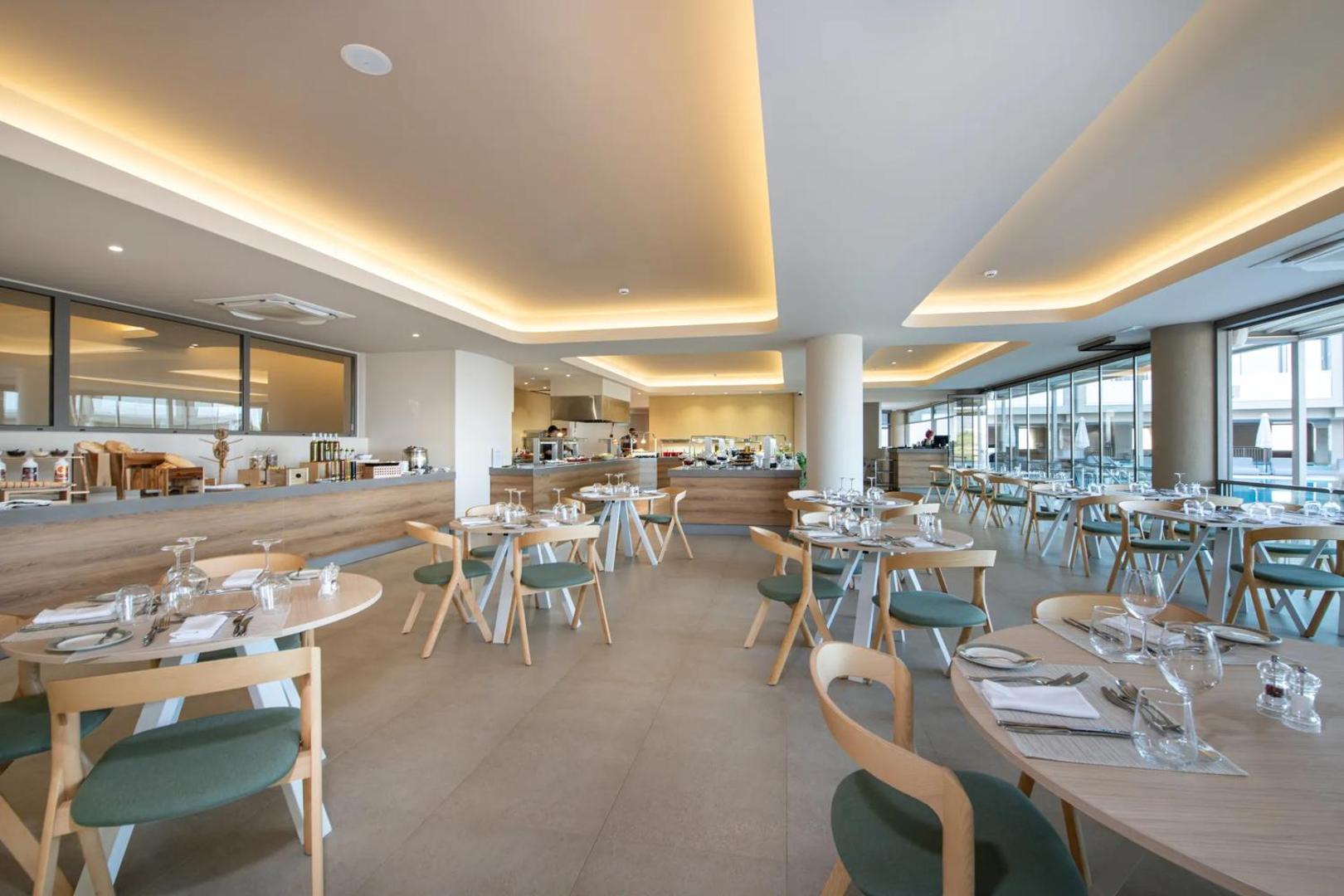 Ventale Island Breeze Resort modernais bufetes tipa restorāns ar gaišu interjeru un servētiem galdiņiem