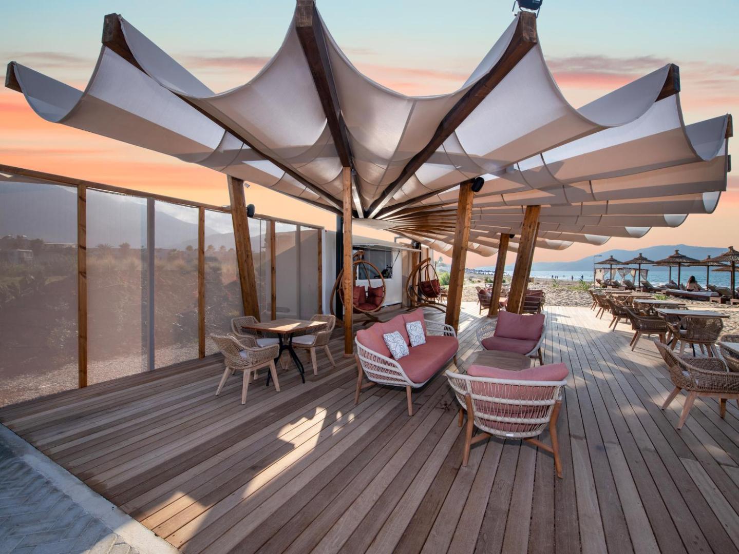 Ventale Island Breeze Resort pludmales bārs saulrietā ar stilīgām mēbelēm, koka terasi un unikālu tentu konstrukciju piekrastē