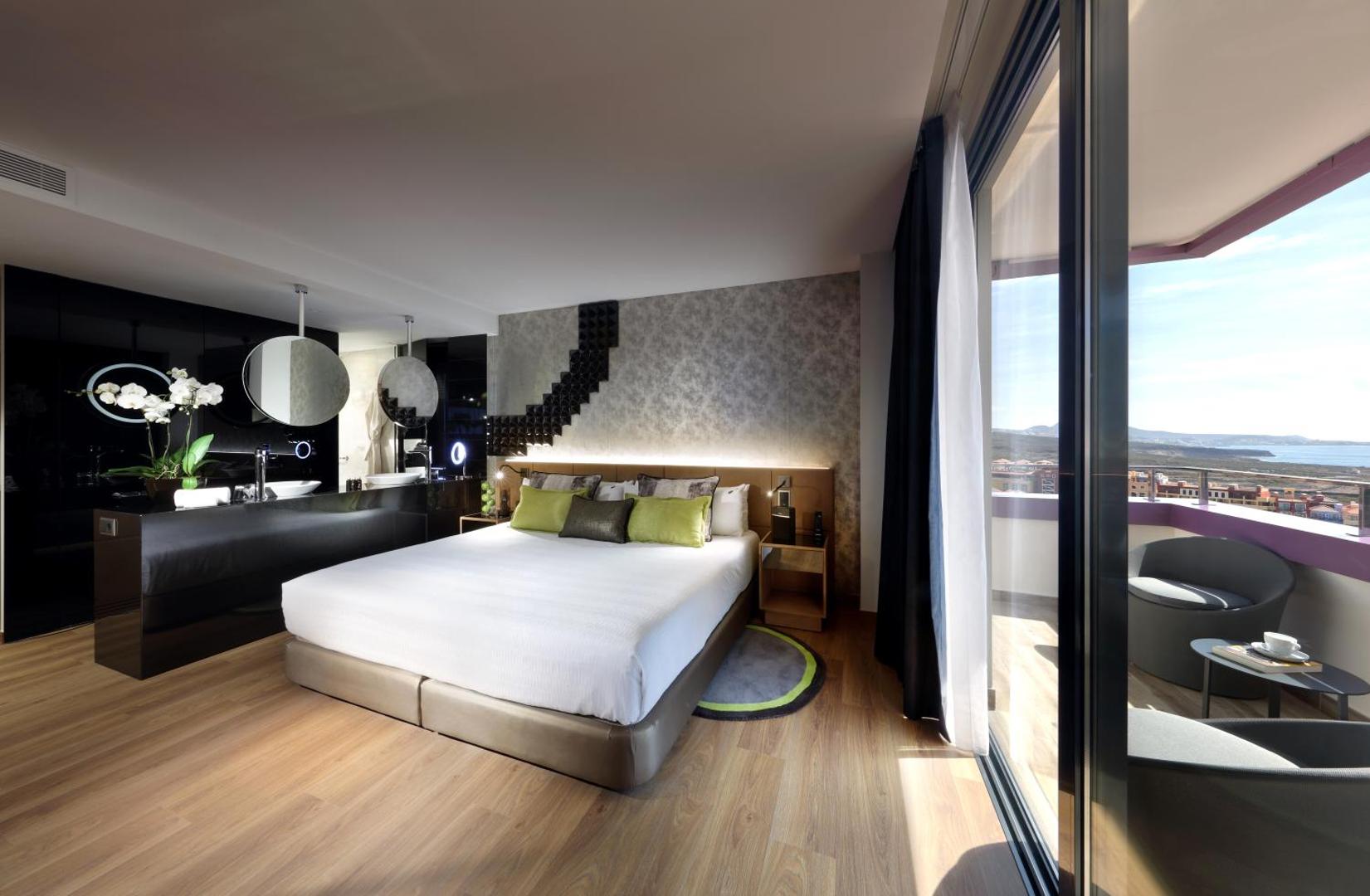 Hard Rock Hotel Tenerife moderns numurs ar skatu uz okeānu, balkonu, atvērtā plānojuma vannas istabu un dizaina mēbelēm Tenerifē.