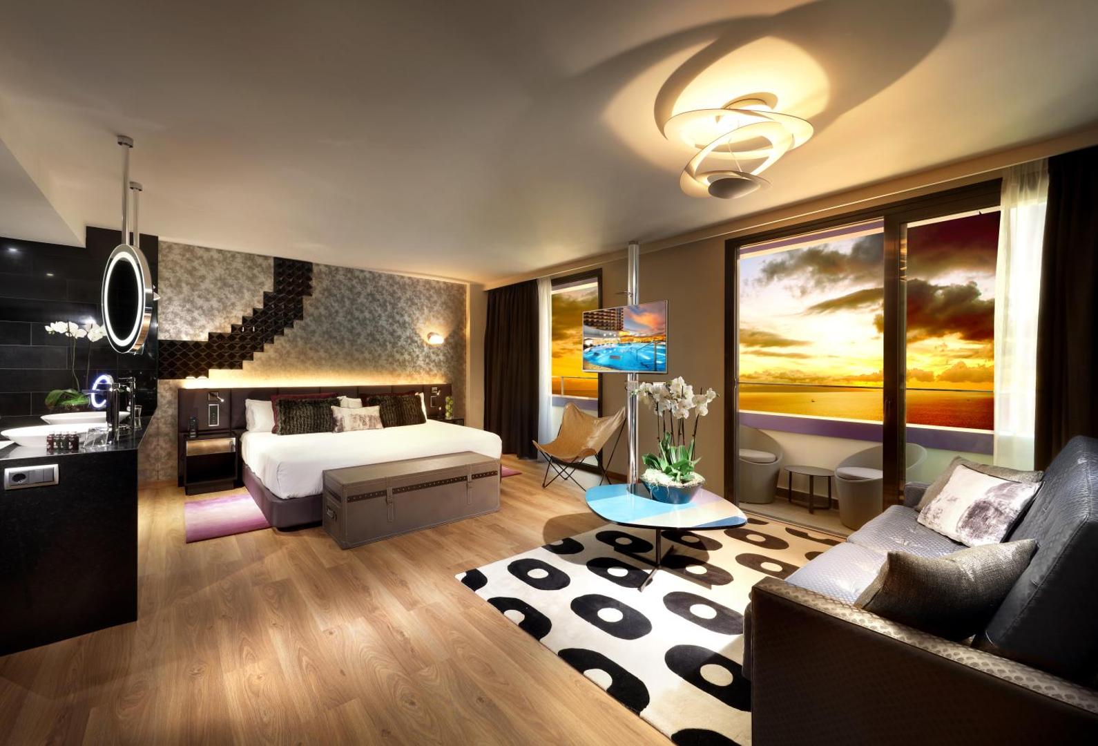 Hard Rock Hotel Tenerife dizaina numurs saulrieta laikā ar skatu uz jūru, modernu apgaismojumu un plašu terasi.