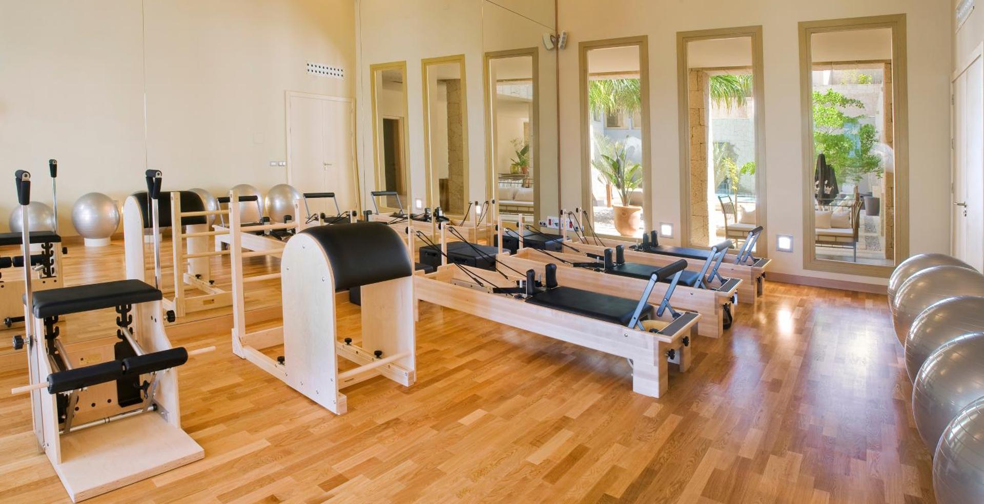 Bahia del Duque pilates studija ar moderniem reformer trenažieriem, gaišu koka grīdu un lieliem spoguļiem fitnesa centrā Tenerifē