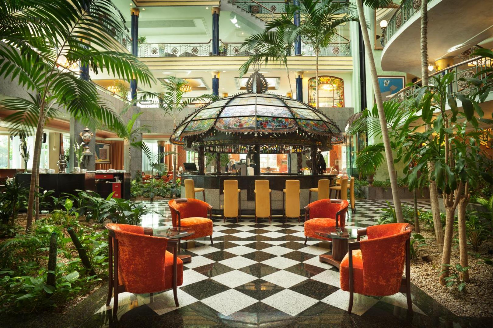 Jardines de Nivaria greznais lobby bārs ar kupolu, palmām un šaha raksta grīdu — plašs atpūtas vestibils Tenerifes kūrortā.