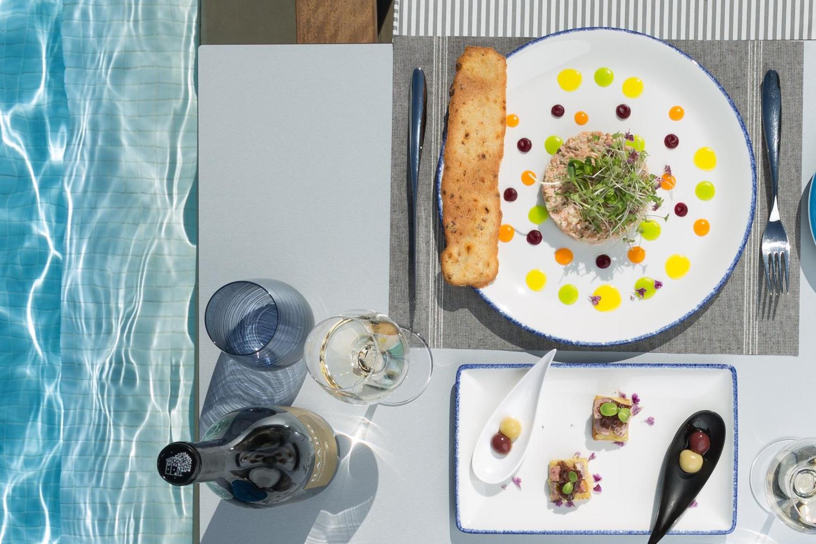 Gourmet uzkodas un vīns uz galda pie baseina Rodostamo Hotel & Spa kūrortā Korfu salā