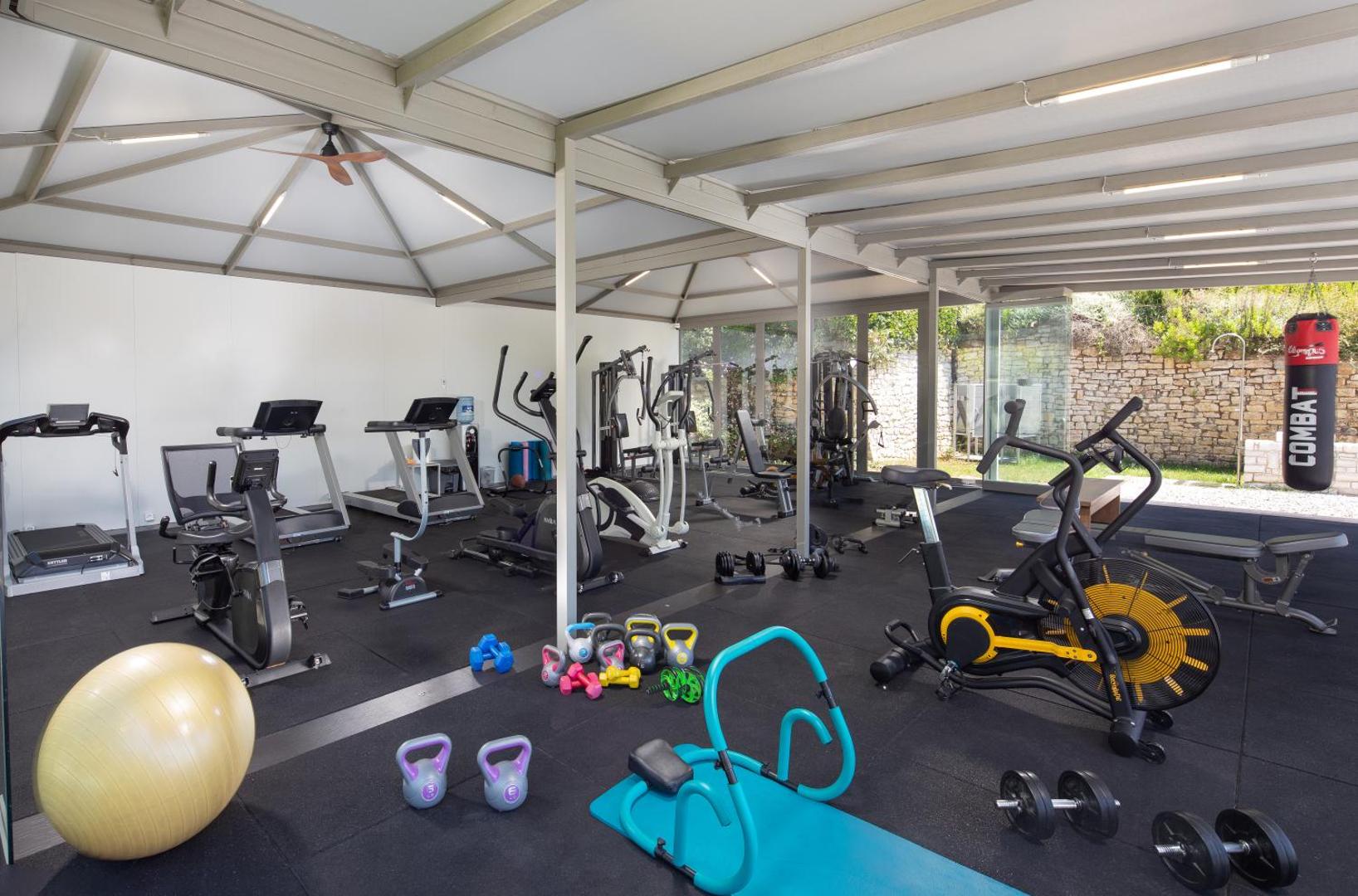 Rodostamo Hotel & Spa fitnesa centrs ar moderniem trenažieriem, brīvajiem svariem un boksa maiss — plaša, gaiša telpa sporta aktivitātēm Korfu salā