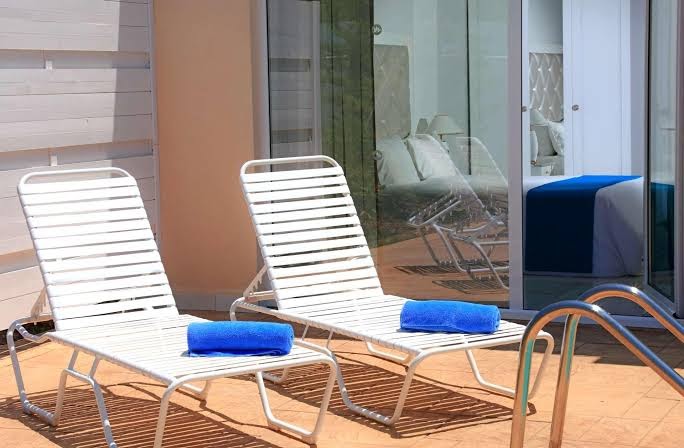 Sandy Villas Resort numurs ar tiešu piekļuvi baseinam — terase ar diviem sauļošanās krēsliem un ziliem dvieļiem pie paša ūdens