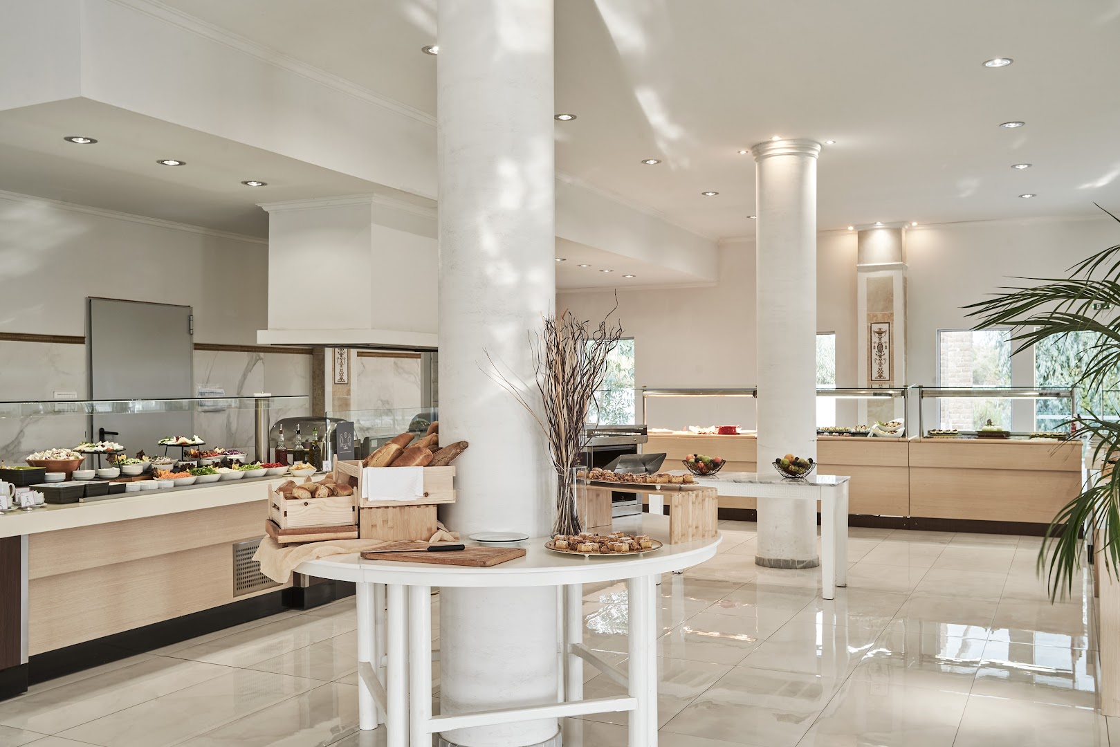 Sandy Villas Resort galvenais restorāns ar bufetes tipa ēdināšanu — gaišs interjers, svaiga maize un plaša uzkodu izvēle