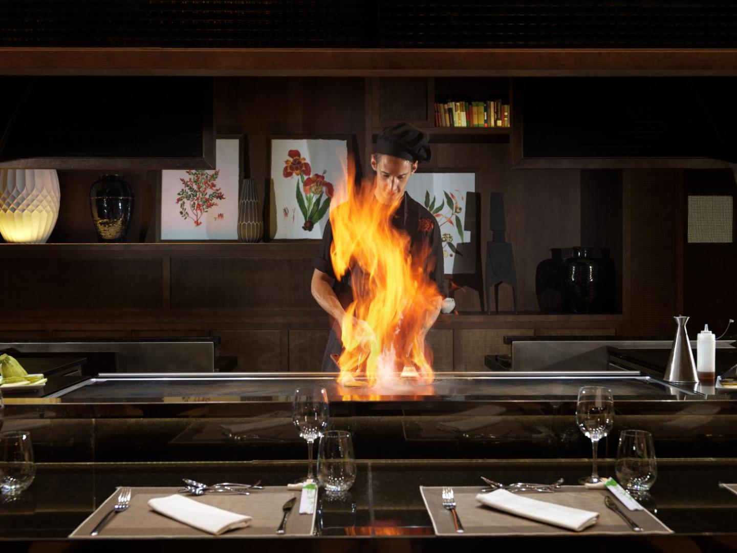 H10 Atlantic Sunset šefpavārs gatavo ēdienu uz atklātas uguns Teppanyaki restorānā, radot kulināru šovu viesiem