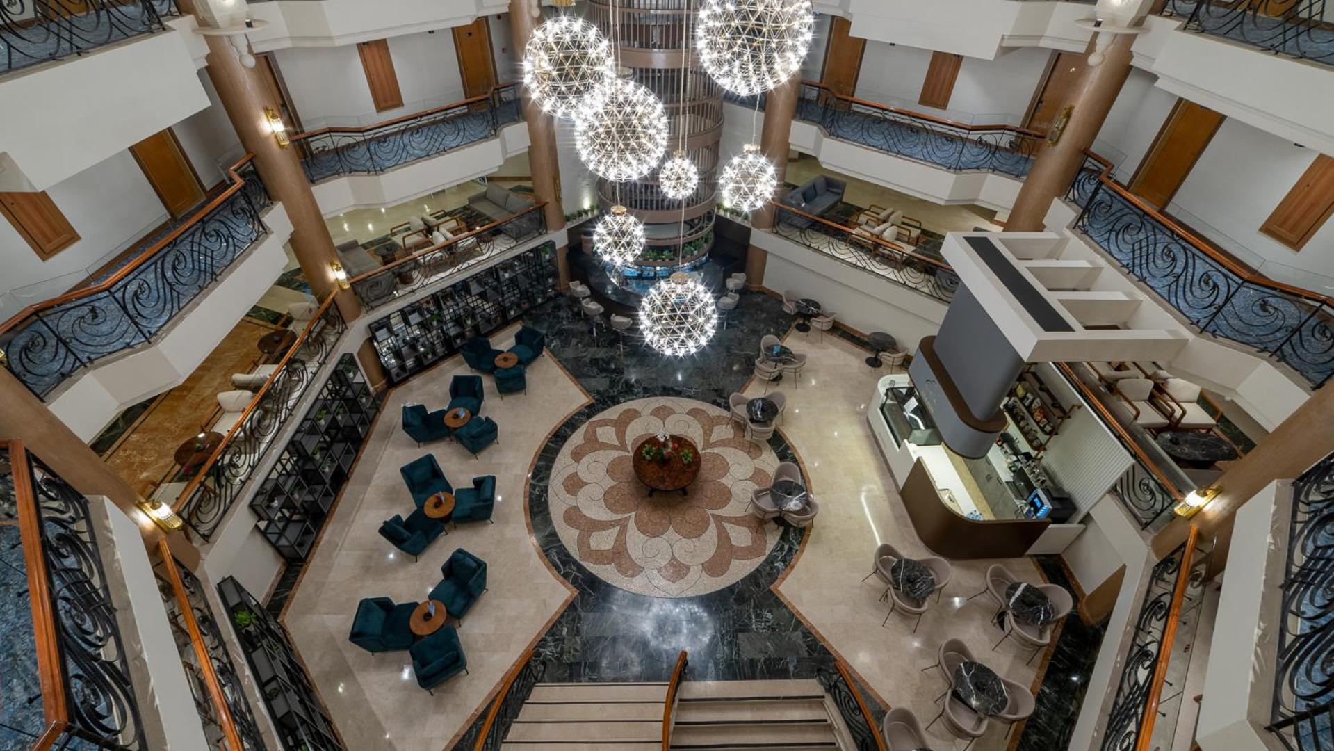Skats no augšas uz Numa Club Side lobby atpūtas zonu ar stilīgiem krēsliem, rakstainu grīdu un iespaidīgu apgaismojumu