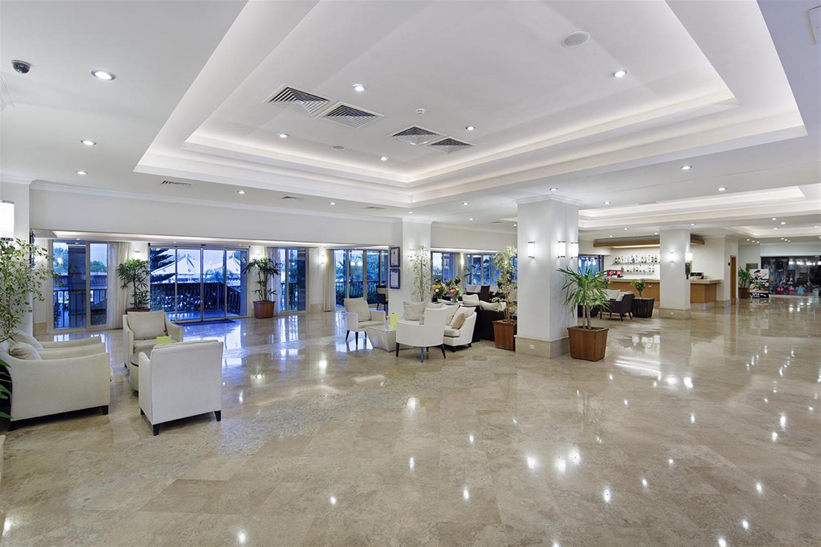Sunis Elita Beach Resort Hotel & SPA plašais vestibils ar marmora grīdu, gaišiem atpūtas krēsliem un lobby bāru tālumā.