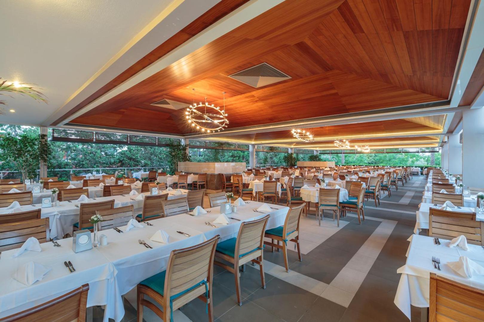 Sunis Elita Beach Resort galvenais restorāns ar koka griestu apdari, modernām lustrām un eleganti klātiem galdiem iekštelpās