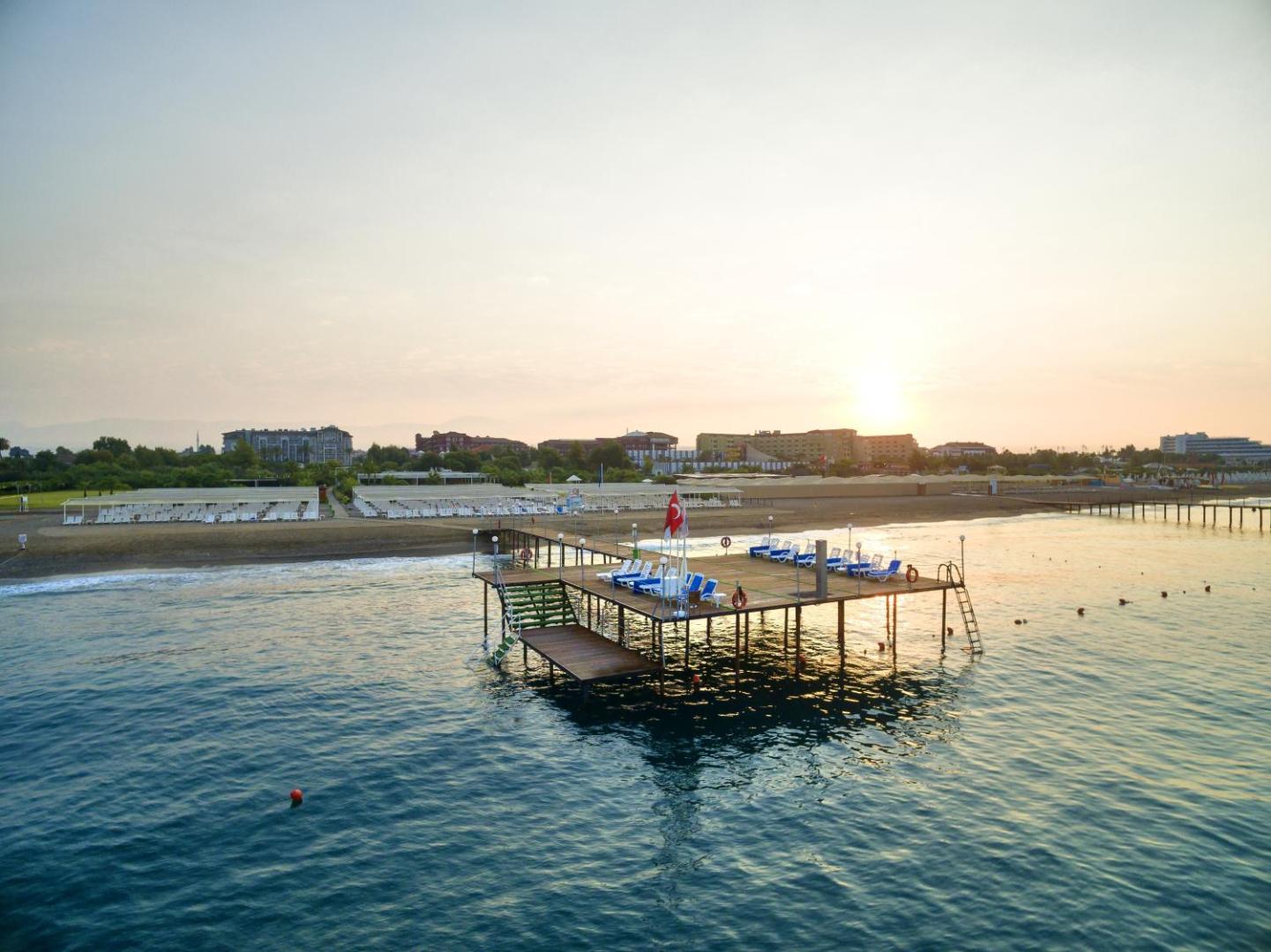 Sunis Elita Beach Resort skats no putna lidojuma uz koka piestātni jūrā saulrieta laikā, Side, Turcija