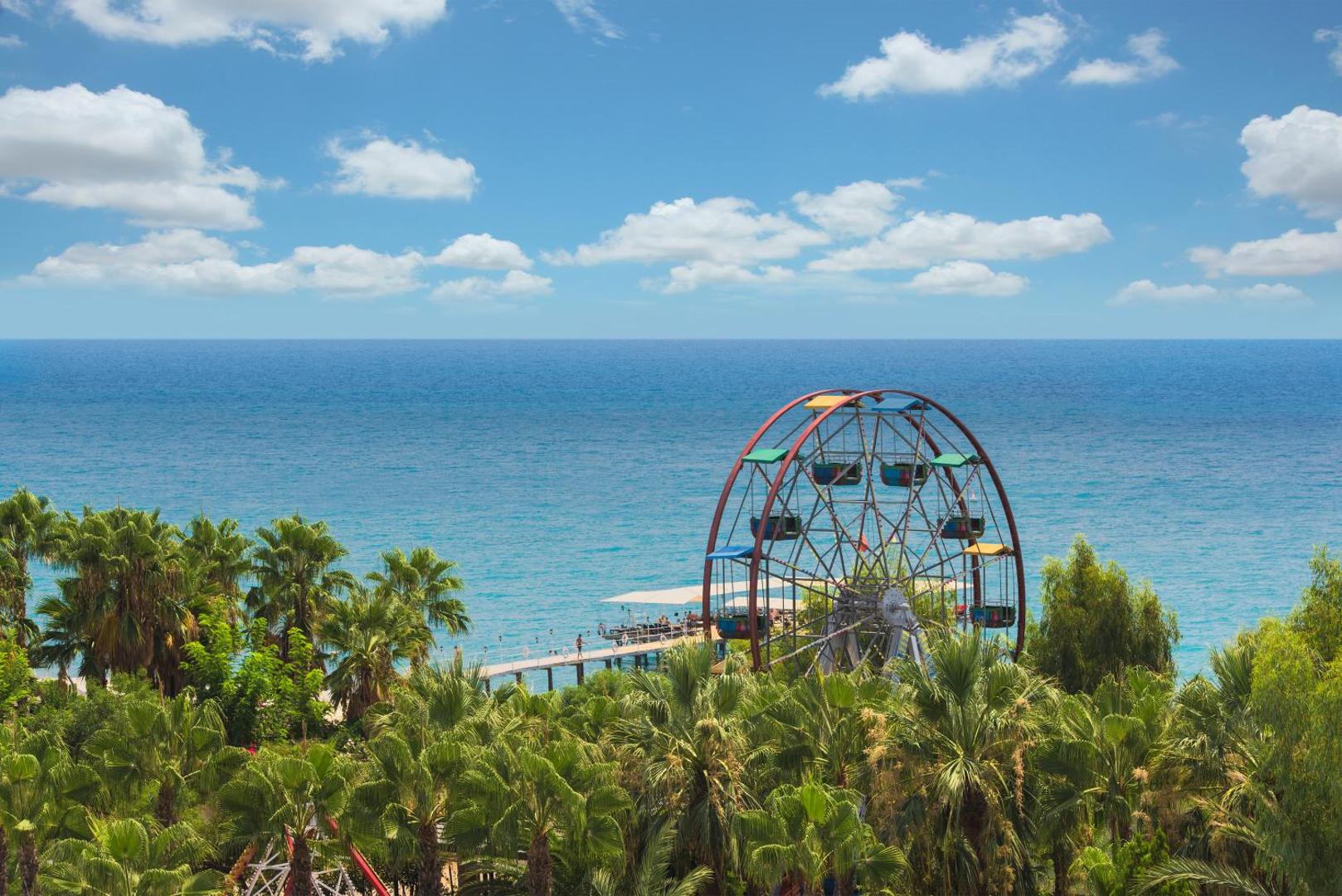 Delphin Deluxe panorāmas rats piekrastē starp palmām ar skatu uz Vidusjūru saulainā dienā Alānijā