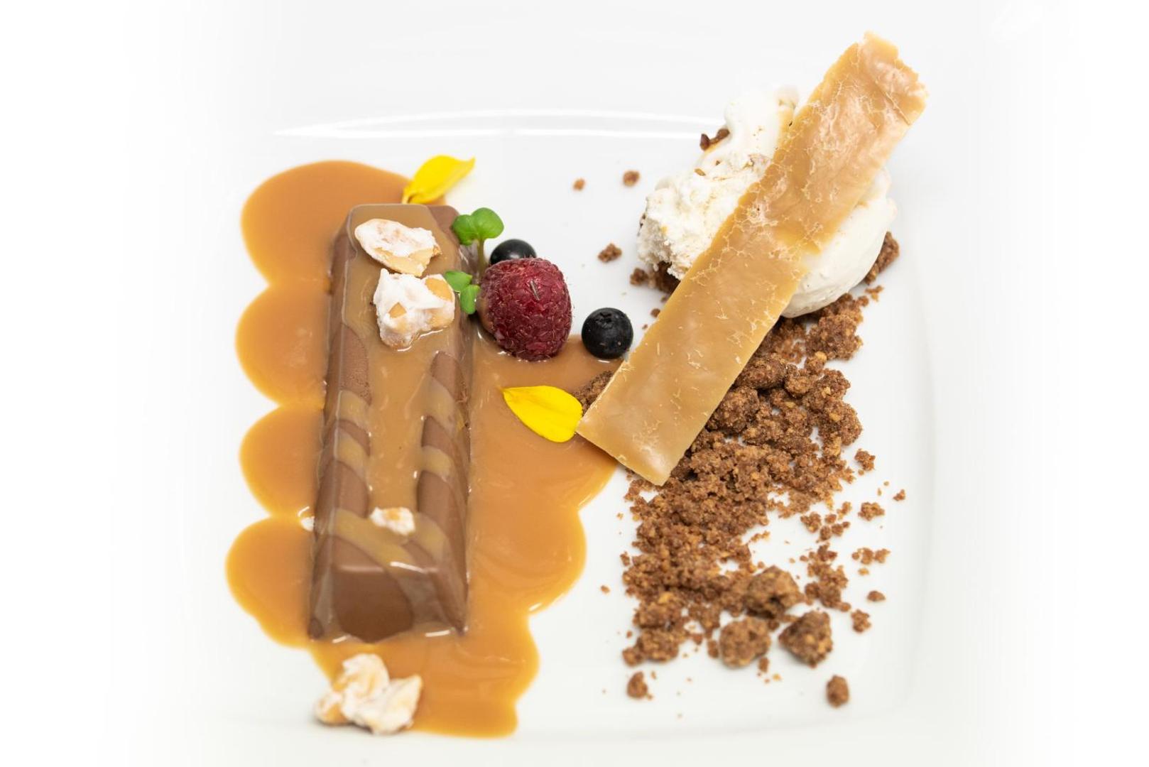GF Gran Costa Adeje restorāna deserts ar šokolādi, karameli un svaigām ogām uz balta šķīvja izsmalcinātai maltītei