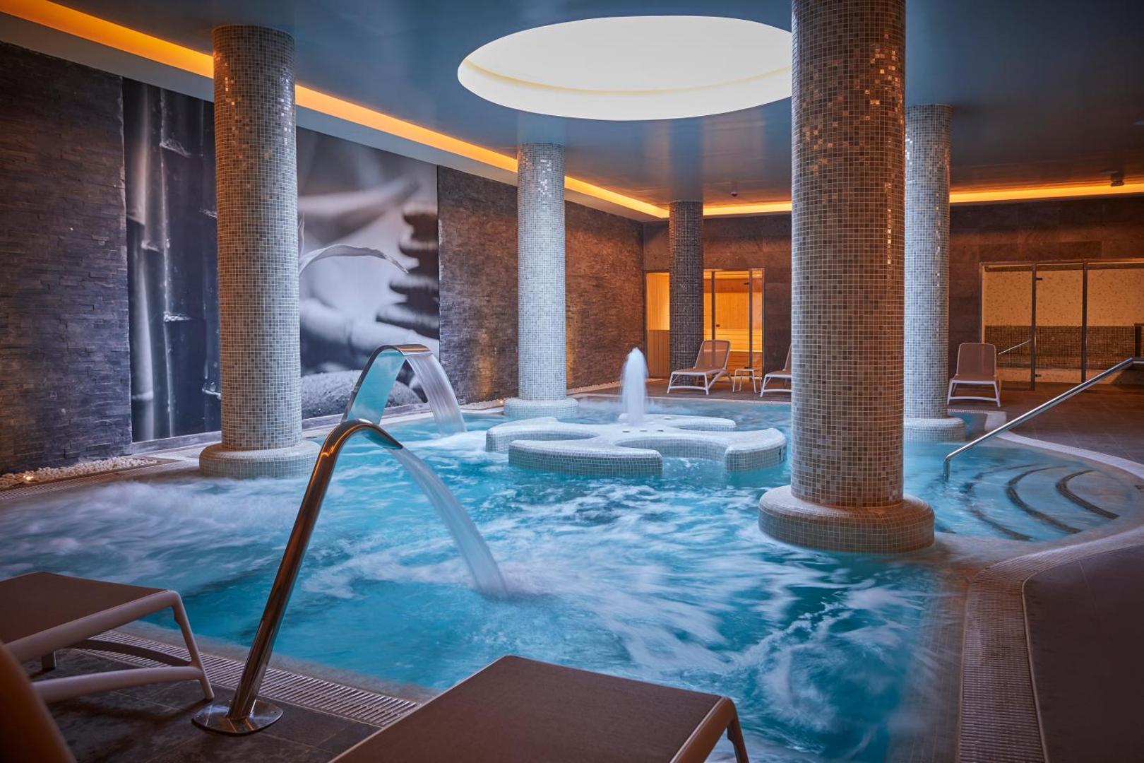 Bahia Principe Fantasia Tenerife iekštelpu spa baseins ar masāžas strūklām, kaskādēm un dekoratīvām kolonnām relaksācijas zonā