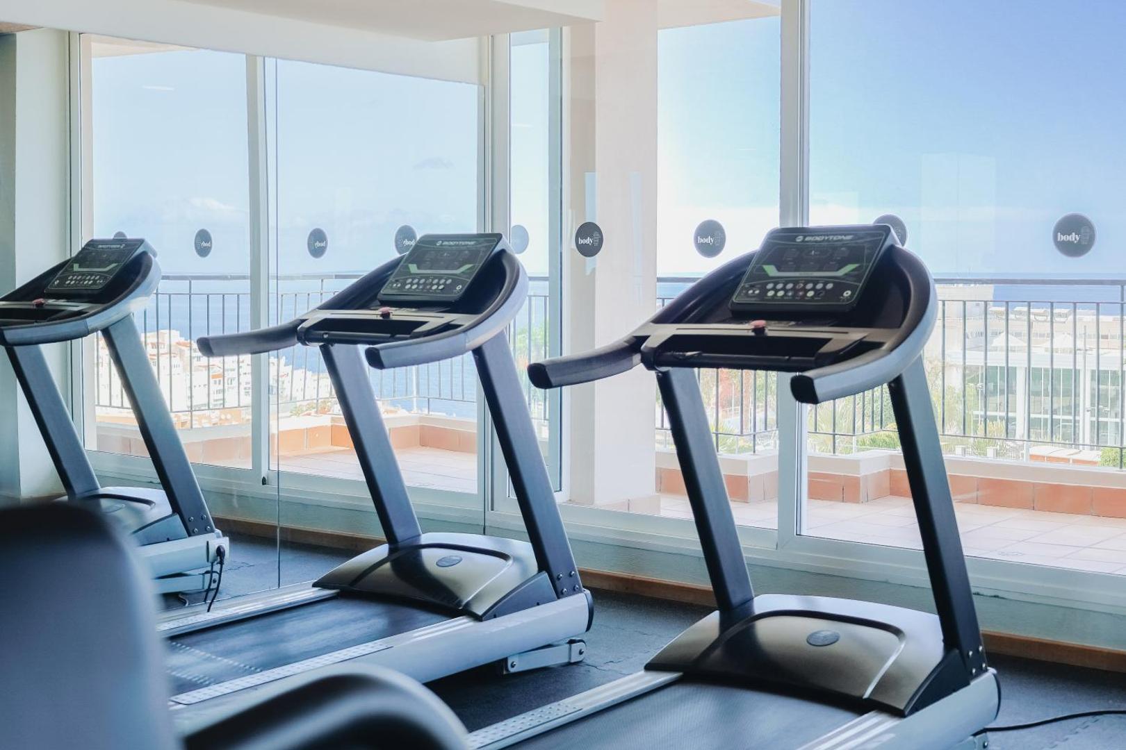 Landmar Costa Los Gigantes fitnesa centrs ar skrejceliņiem un skatu uz okeānu Tenerifē — mūsdienīgs sporta aprīkojums gaišā telpā