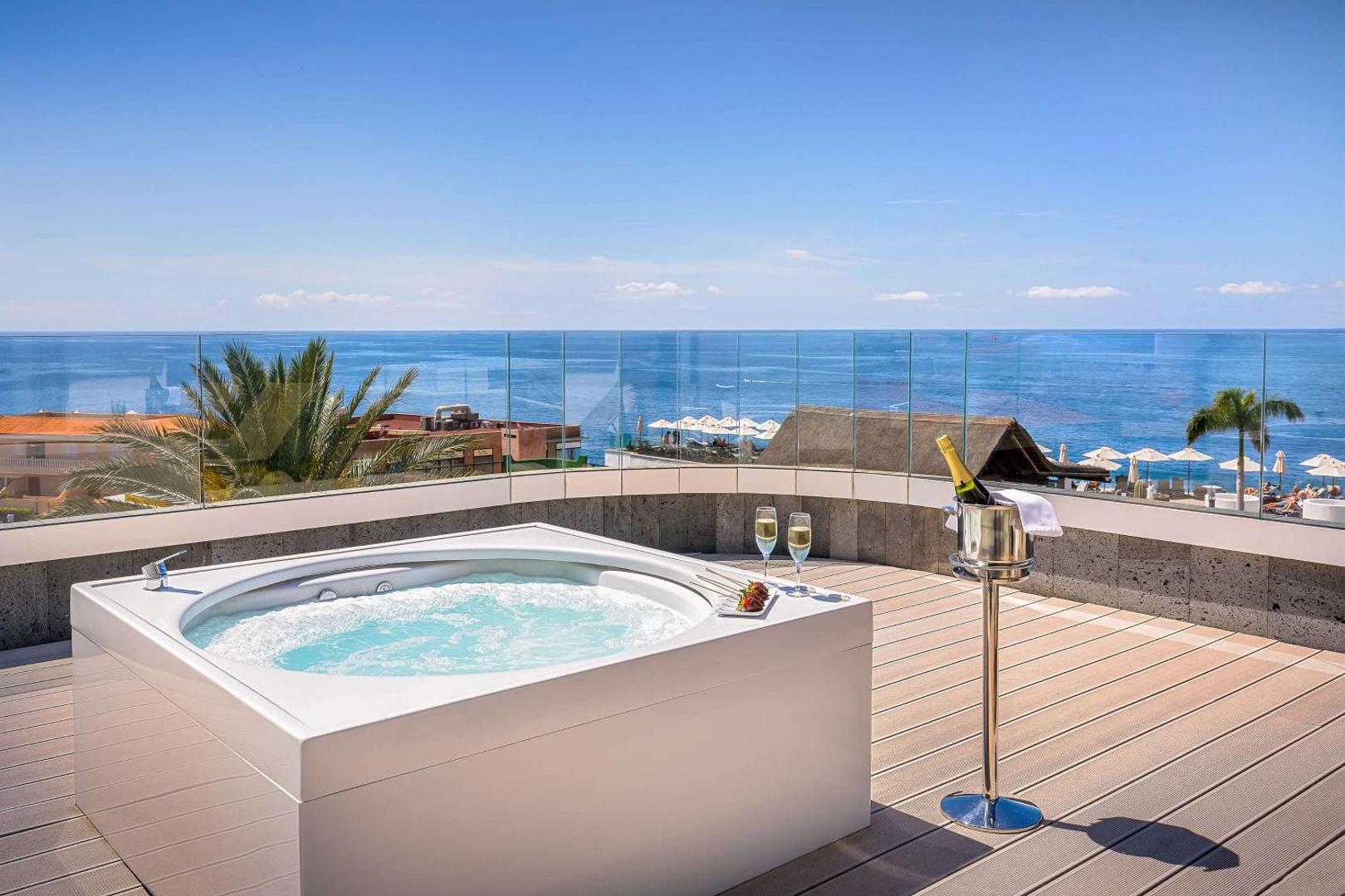 Barcelo Santiago viesnīcas numura terase ar privātu džakuzi, šampanieti un skatu uz Atlantijas okeānu Tenerifes piekrastē saulainā dienā