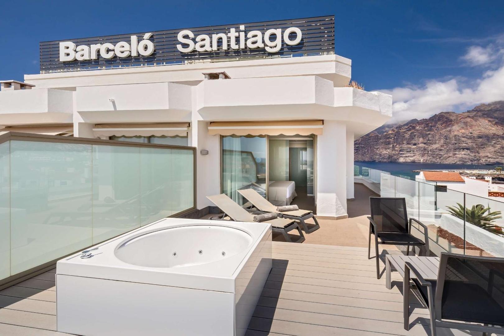 Barceló Santiago viesnīcas numura terase ar džakuzi, sauļošanās krēsliem un skatu uz Los Gigantes klintīm Tenerifē, Spānijā.