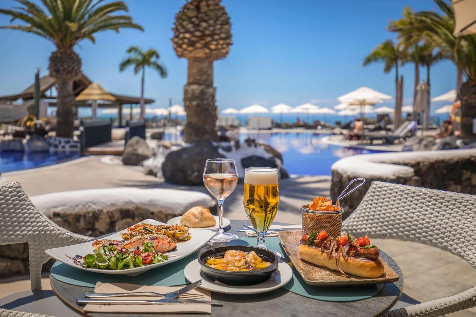 Barcelo Santiago viesnīcas restorāna terase ar uzkodām, vīnu un alu pie baseina Tenerifes saulē