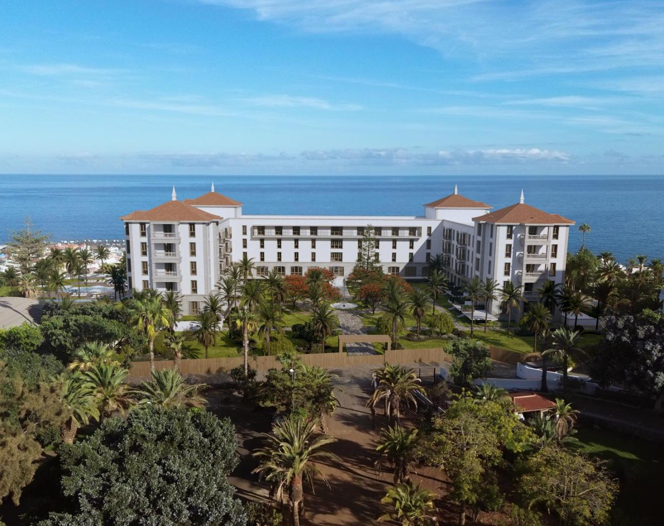 Gran Hotel Taoro ēka no putna lidojuma Puertodelakrusā — plašs dārzs ar palmām un skats uz zilo Atlantijas okeānu