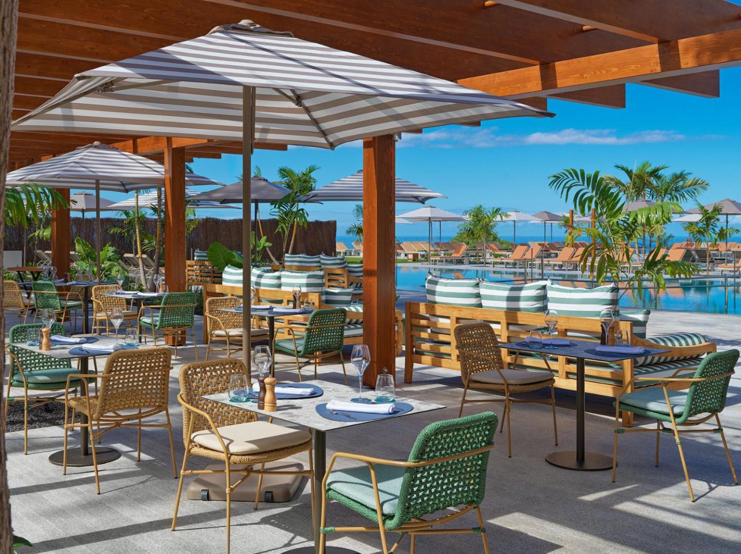 Gran Hotel Taoro āra bārs un atpūtas zona zem koka nojumes ar pītiem krēsliem un skatu uz baseinu Tenerifes kūrortā.