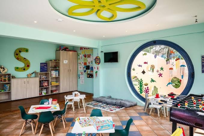 Sentido Apollo Palace krāsains bērnu klubs ar rotaļu galdiem, spēlēm un radošo stūrīti — plaša iekštelpu atpūtas zona bērniem Korfu kūrortā