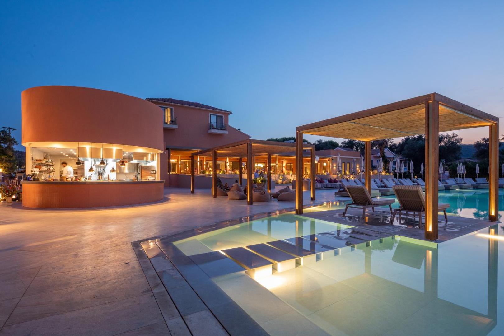 Sentido Apollo Palace vakara apgaismojums pie baseina un bāra zonas Korfu — moderna arhitektūra un mājīga atmosfēra saulrietā