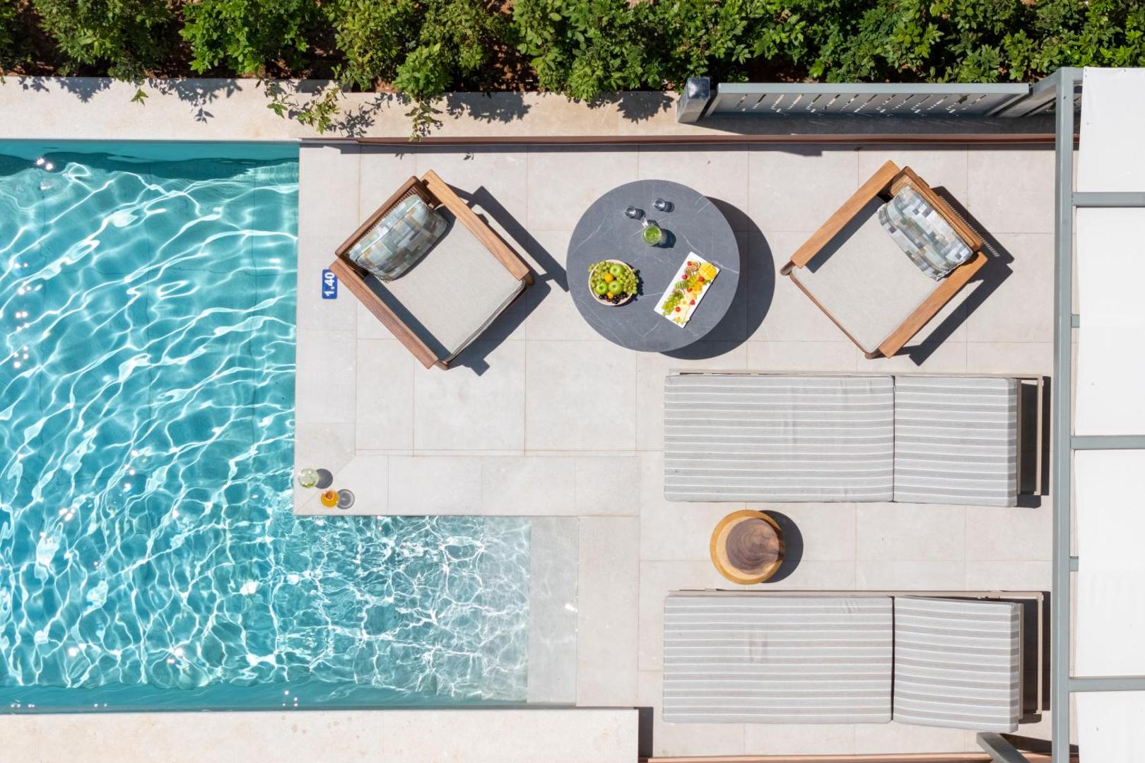 Sentido Apollo Palace numurs ar tiešu piekļuvi baseinam — privāta terase ar atpūtas krēsliem, galdiņu un augļu plati