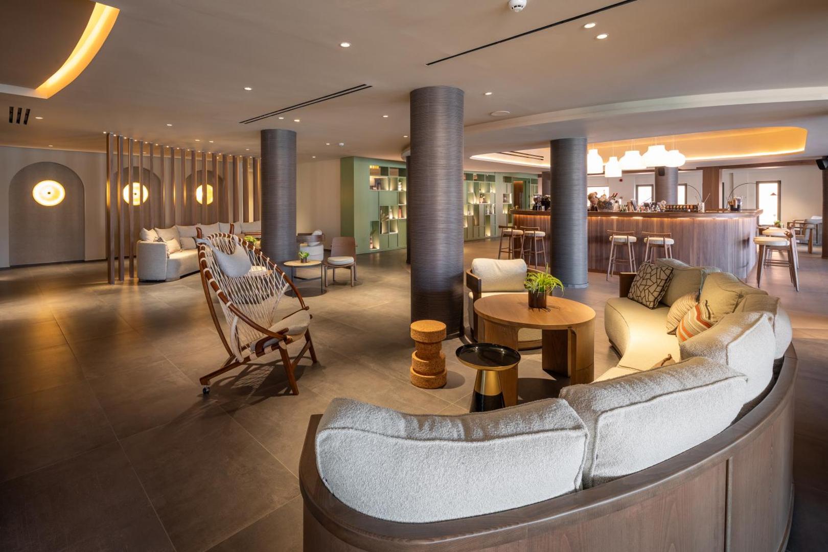 Sentido Apollo Palace viesnīcas lobby atpūtas zona ar modernām mēbelēm, dizaina krēsliem un siltu apgaismojumu Korfu kūrortā