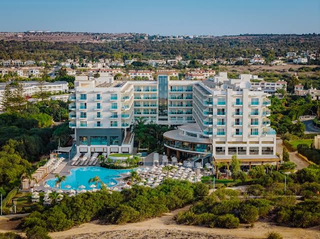 Nissiblu Beach Resort panorāmas skats no putna lidojuma Aijanapā — plašs āra baseins, sauļošanās zona un viesnīcas korpusi pie jūras
