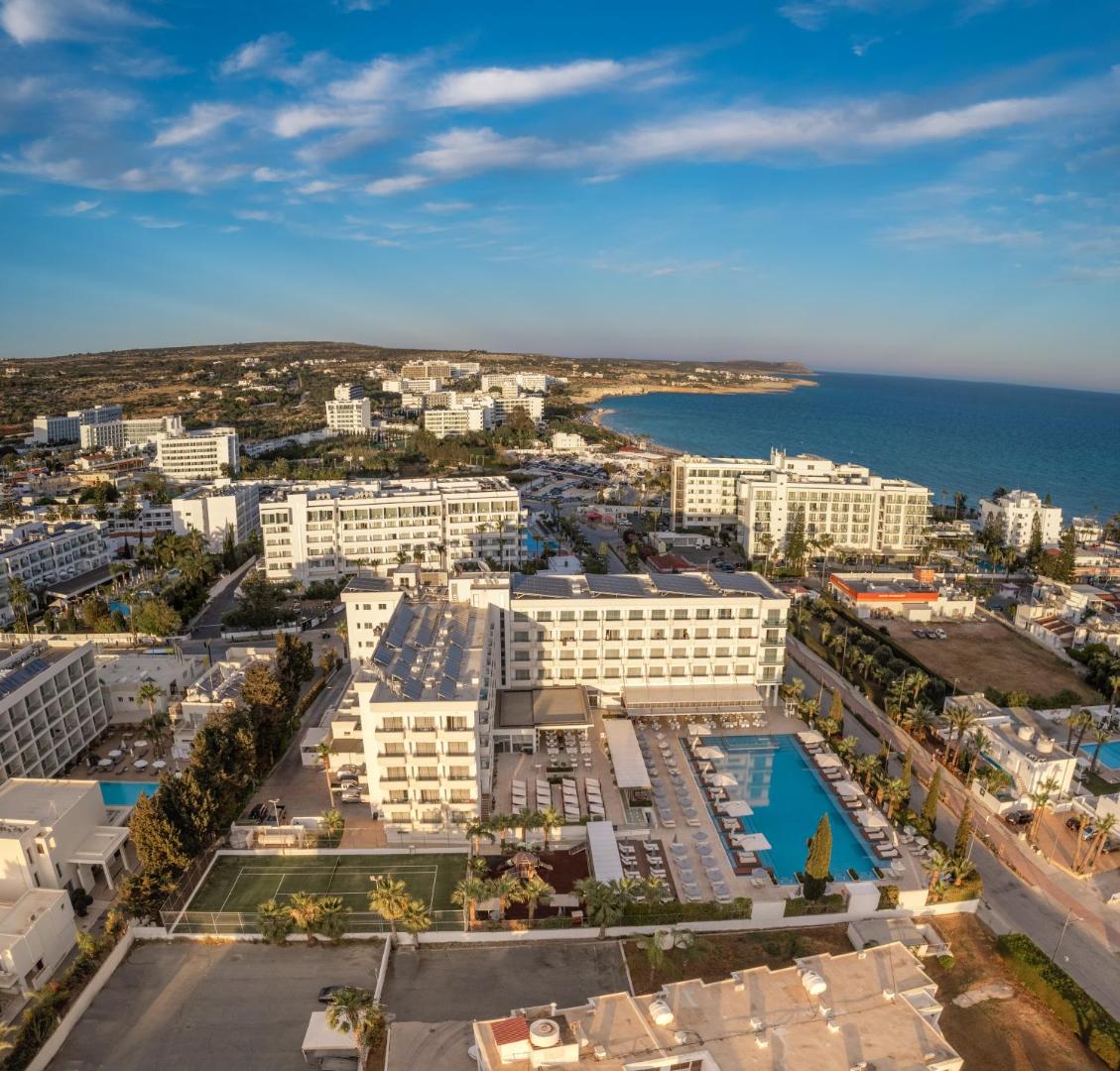 Nestor Hotel teritorijas aerofoto ar lielu āra baseinu, tenisa kortu un skatu uz Vidusjūras piekrasti Aijanapā